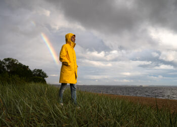 Man in yellow raincoat with hood walk on the beach in rainy weat - Arriva la neve: emozione e speranza per ogni appassionato di meteo