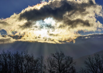 Sunrise with the sun through the clouds and sunbeams coming out of the snowy mountains. - Meteo: Weekend di alta pressione, ma ci sono novità