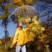 an emotional woman with autumn leaves and a transparent umbrella in front of yellow leaves in bright weather - Meteo: anticiclone troppo forte, è già finita l’autunno?