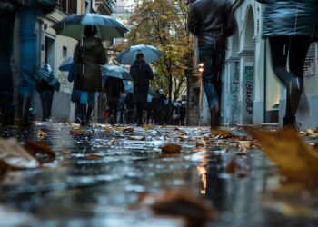 Blur obscures faces as people walk by with rain gear and leaves litter the wet - L’Italia e l’impatto devastante delle alluvioni, clima sempre più estremo