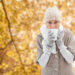 Woman in warm clothing holding mugs against tranquil autumn scene in forest - Meteo grigio e mite? Aspettiamo novembre, porterà il freddo