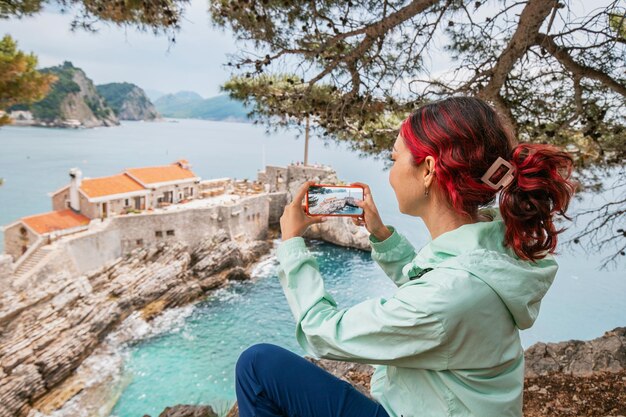 una donna viaggiatrice si trova di fronte un vecchio castello o forte di petrovac sulla costa del montenegro e scatta una foto con lo smartphone 984126 17699 - Viaggio a Korčula, Croazia: scoperte e fascino dell’antica isola veneziana