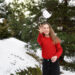 A young woman throws a snowball at the camera against the background of Christmas trees, winter activity and fun. new year and holidays concept - Meteo: Mercoledì 20, possibile neve su alcune regioni, ecco quali