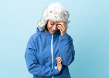 Young Uruguayan girl with winter hat isolated on blue background laughing - Meteo: da domenica calore africano su metà dell’Italia