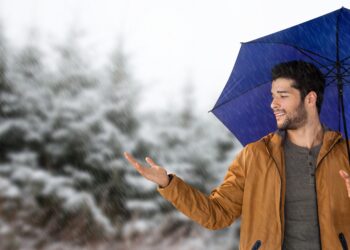 Digital composite of Man with blue umbrella in snow forest - Previsioni meteo dicembre, Immacolata sotto zero: neve per Natale