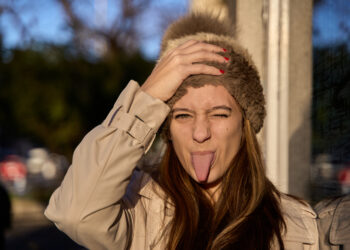 portrait of a woman at sunset looking at the camera with a woolen hat sticking out her tongue with a funny face - Meteo, arriva un nucleo gelido: ecco cosa aspetta l’Italia