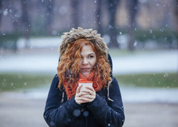 red hair woman holding a cup of hot coffee - Cambiamento climatico, ecco dove farà molto freddo