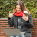 Young woman working on laptop sitting on a park bench with coffee. Computer and online shopping use. Distance learning, online education. - Meteo: freddo notturno, ci prepariamo per le prime gelate