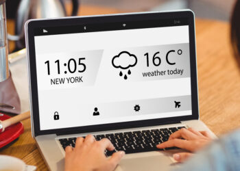 Home screen on a mobile display against woman using laptop at office - Meteo: inizia la settimana con tempo stabile ma possibili temporali