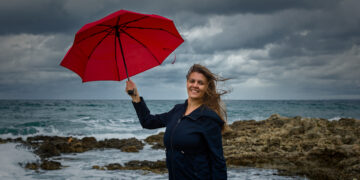 Young woman with a red umbrella on the background of the sea - DIRETTA METEO, News Meteo, Previsioni Meteo, Viaggi