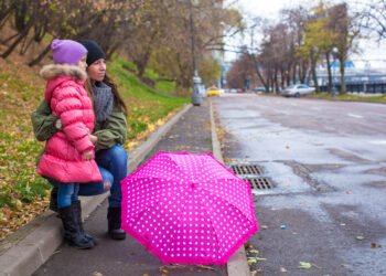 Little girl and her ​​mother walking  with umbrella on a rainy day - Meteo: ciclone previsto per il ponte dell’Immacolata, regioni a rischio