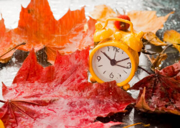 retro yellow clock and yellow autumn leaves on a black background, concept, fall, falling, as the substrate, flat lay - Meteo: il clima sarà meno freddo nei prossimi giorni, durerà?