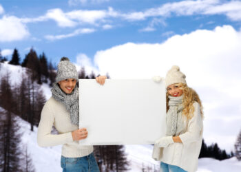 smiling couple in winter clothes with blank board - Cambiamento climatico nella terza settimana di ottobre: cosa aspettarci