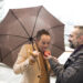 An executive offers a red apple to another who sucks it under the umbrella on a rainy day - Meteo: diciamo addio al freddo a Natale, che brutta sorpresa!