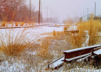 The railroad goes into the distance illuminated by the sun. Railroad covered with snow. - Paradosso meteo: alta pressione ma cielo grigio e pioggia