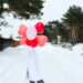 Happy woman without a face with heart-shaped balloons outdoor in winter with snow. Valentine’s Day, love and infatuation, a gift from a boyfriend, a declaration of love, lifestyle - Meteo: un Natale diverso